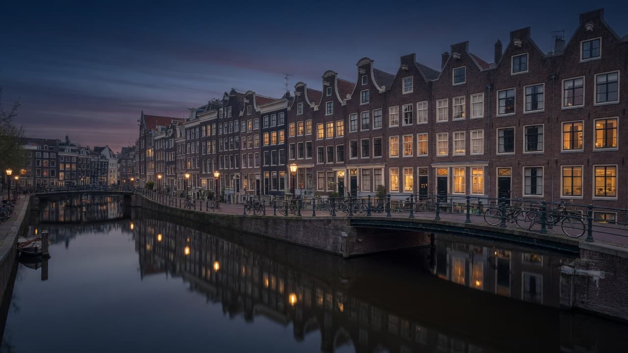 Amsterdam canal houses at dusk reflected in still water